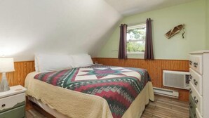 A bedroom with a bed, a nightstand, a dresser, a window with curtains, and a radiator. - Artilla Cove Resort # 9 (Branson)