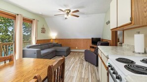 A compact living space with a dining table, sofa, TV, and kitchen area including a stove. - Artilla Cove Resort # 9 (Branson)