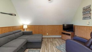 A modern living room with a sectional sofa, a flat-screen TV, and a wall-mounted shelf. - Artilla Cove Resort #10 (Branson)