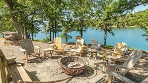 A lakeside campsite with Adirondack chairs, a fire pit, and a wooden deck. - Artilla Cove Resort #10 (Branson)