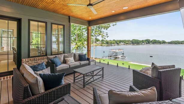 A covered outdoor seating area with wicker furniture, a ceiling fan, and a view of a lake. - The Retreat at Sunrise Cove (Sherrills Ford)