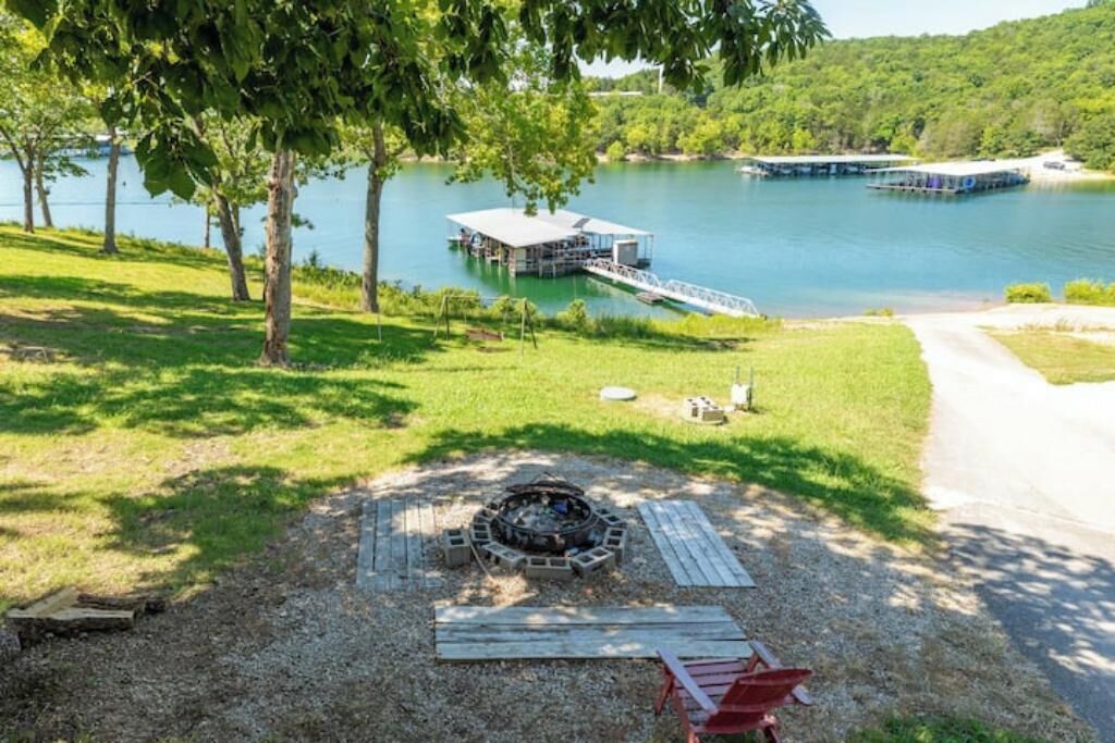 A lakeside property with a dock, a fire pit, and a covered seating area.