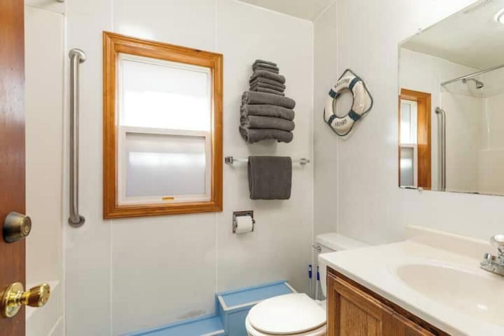 Een badkamer met een wit toilet, een wastafel, een spiegel, een handdoekhouder en een douchehoek.