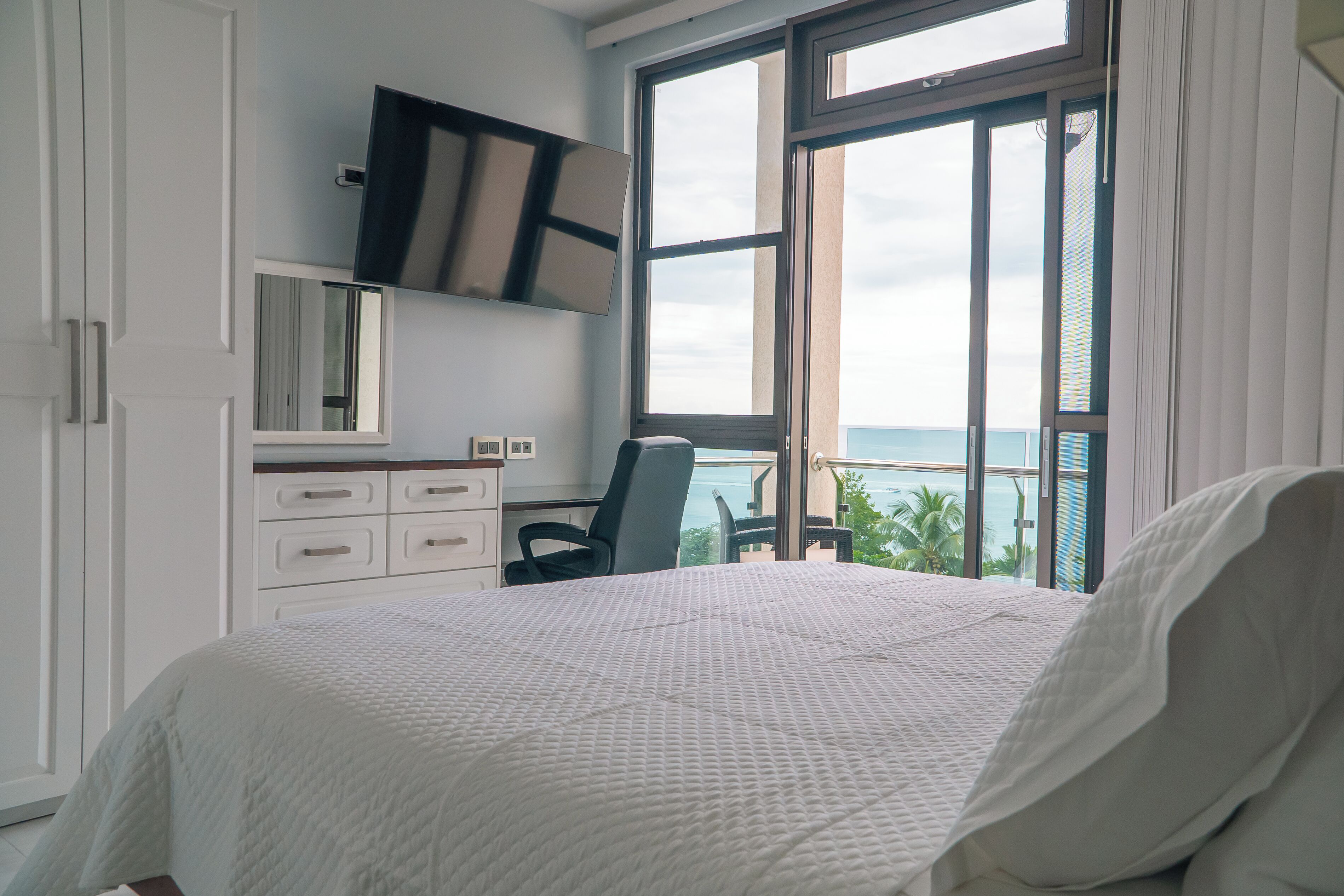 Ein Schlafzimmer mit einem großen Bett, einem Schreibtisch und Meerblick.