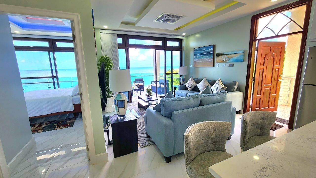 A modern living room with a sofa, chairs, a coffee table, and a view of the ocean.