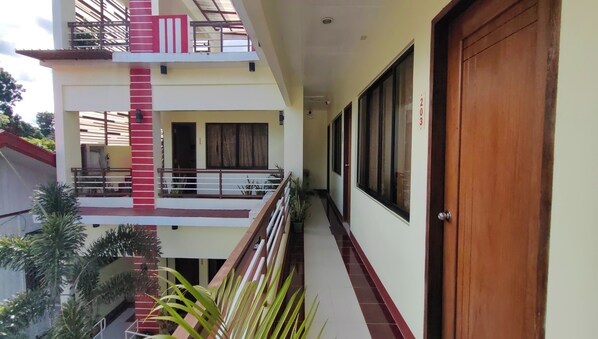 A multi-level building with balconies, a wooden door, and a tiled floor. - Pring Pension House Puerto Princesa By Zuzu (Puerto Princesa)