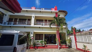 A two-story building with a balcony, air conditioning units, and a parked van. - Pring Pension House Puerto Princesa By Zuzu (Puerto Princesa)