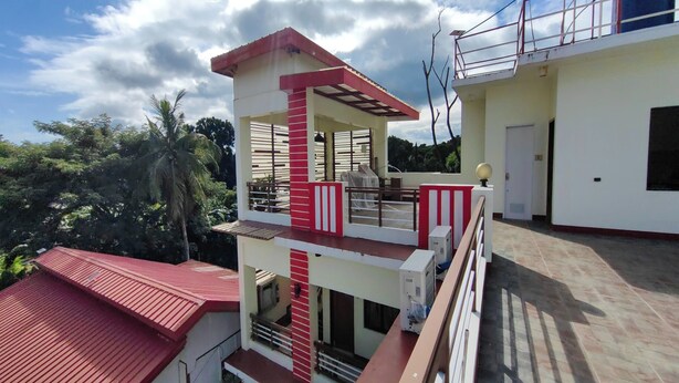 Um edifício de vários andares com esquema de cores vermelho e branco, varandas e vista para o verde ao redor.