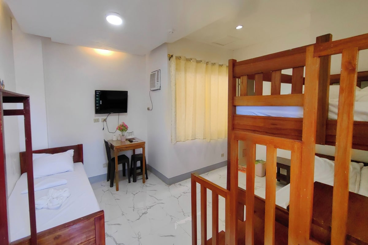 Una habitación con literas, un escritorio, una televisión y una ventana con cortinas.
