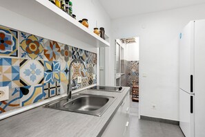 Una cocina moderna con un lavamanos doble, armarios blancos y un brillante mosaico en la pared.
