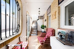 Un couloir étroit avec un escalier, une chaise à motifs à carreaux et une machine à coudre posée sur une table.