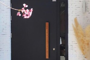 A black door with a vertical sign and a branch with pink flowers. - THE ARIX House & Studio (Dalat)