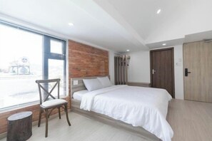 A modern bedroom with a large window, a wooden headboard, a bed with white bedding, and a wooden door. - THE ARIX House & Studio (Dalat)