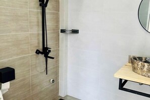 A bathroom with a shower, a toilet paper holder, a sink with a marble basin, and a mirror on the wall. - THE ARIX House & Studio (Dalat)