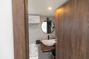 A bathroom with a wooden vanity, a round mirror, and a white sink. - THE ARIX House & Studio (Dalat)
