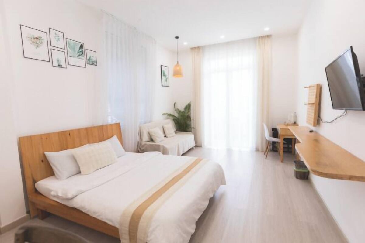 Ein modernes Hotelzimmer mit einem hölzernen Bett, einem Schreibtisch, einem Stuhl, einem Fernseher und gerahmten Bildern an der Wand.