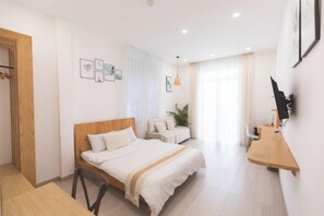 A modern hotel room with a wooden bed, a desk, and a TV. - THE ARIX House & Studio (Dalat)