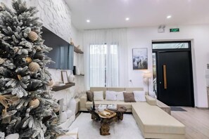 A modern living room with a large Christmas tree, a sofa set, and a coffee table. - THE ARIX House & Studio (Dalat)