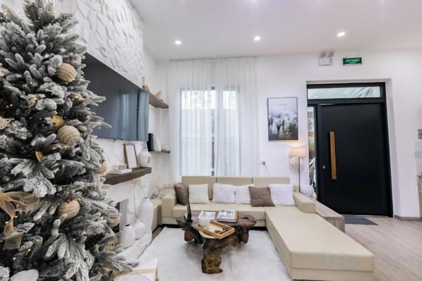 A modern living room with a large Christmas tree, a sofa set, and a coffee table. - THE ARIX House & Studio (Dalat)
