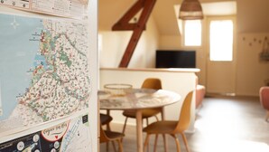 Een eethoek met een ronde tafel en stoelen, een houten plafondconstructie en een muur met een kaart.