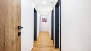 A narrow hallway with wooden flooring, white walls, and dark doors. - Room '1 - Cozy' with Wi-Fi (Fieberbrunn)