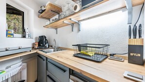 A kitchen with a wooden countertop, a sink, a dish rack, and a knife block. - Room '1 - Cozy' with Wi-Fi (Fieberbrunn)