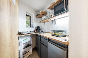 A compact kitchen with a microwave, coffee maker, and wooden shelves. - Room '1 - Cozy' with Wi-Fi (Fieberbrunn)