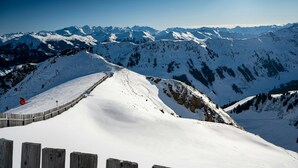 A snow-covered mountain landscape with a wooden fence and a clear sky.