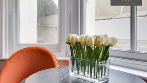 Un vaso di vetro trasparente con tulipani bianchi su un tavolo vicino a una finestra.
