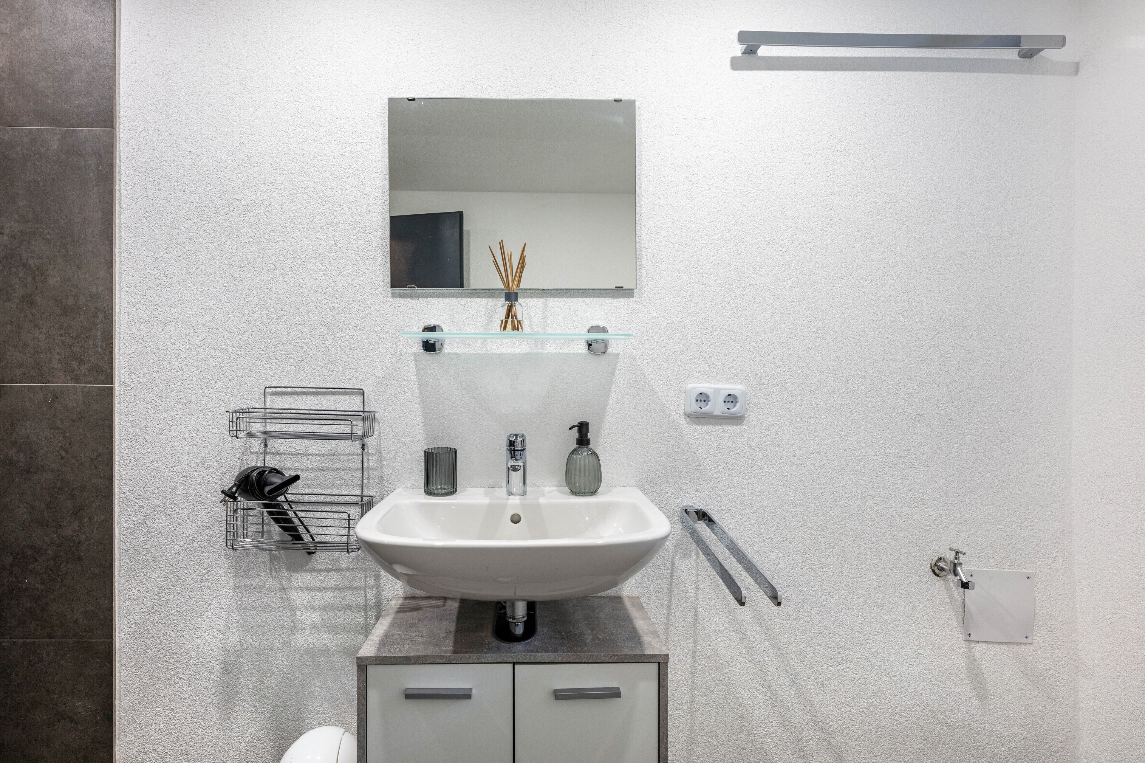 A bathroom with a white sink, mirror, and towel rack.