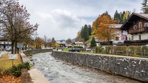 Un río que corre junto a un muro de piedra con un edificio de madera a la derecha.