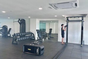 A gym with exercise equipment, including dumbbells, a treadmill, and a pull-up bar. - 121 Residences by manatidur (Petaling Jaya)