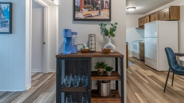 A modern kitchen with a coffee machine, a plant, and a sign that reads "crossed blessed."