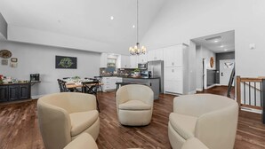 A spacious living room with a dining area, a kitchen with white cabinets, and a staircase leading to another level.