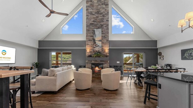 A spacious living area with a fireplace, high ceilings, and large windows.