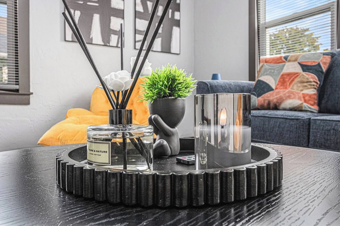 Una sala moderna con una mesa de centro, una planta en maceta, una vela y un adorno decorativo.