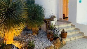 A white building with a tiled entrance, potted plants, and a stone pathway leading to the entrance. - Casa Bonic: Villa with Sunset - seaview and pool (Sant Josep de sa Talaia)