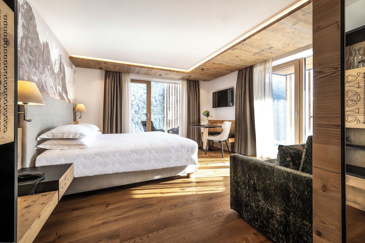 Ein modernes Hotelzimmer mit einem großen Bett, einem Schreibtisch und einem bequemen Sessel.