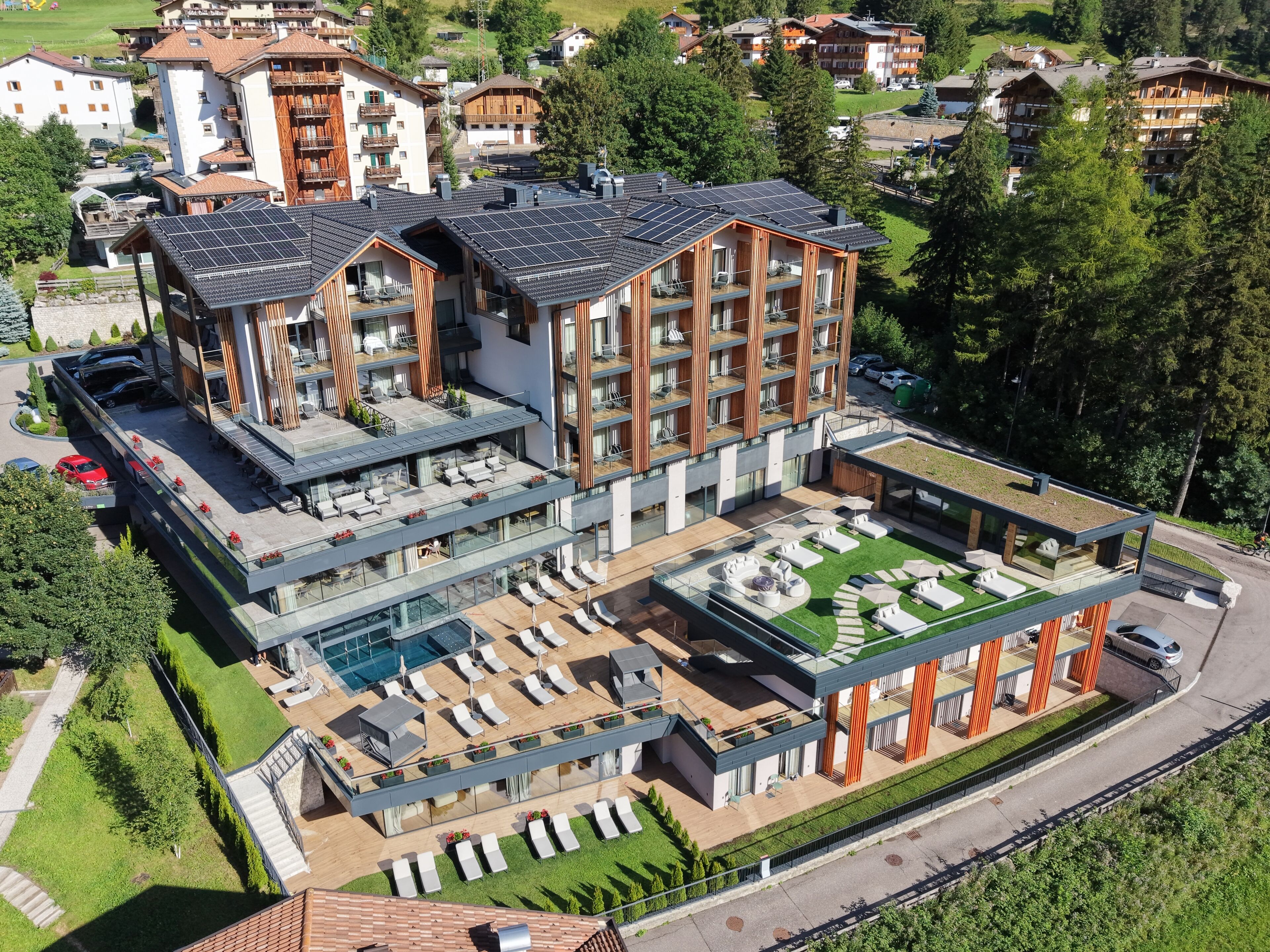 A modern hotel with multiple floors, outdoor seating areas, and a swimming pool.