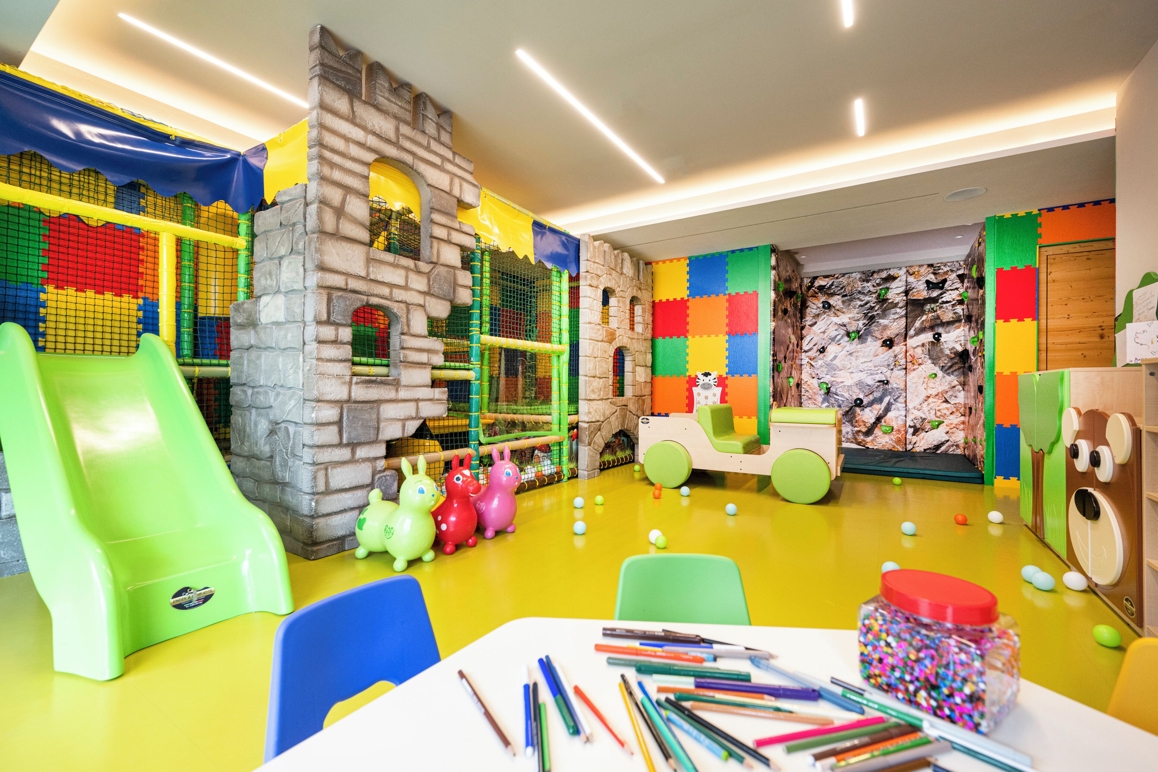 A children's play area with a slide, climbing walls, and a playhouse.