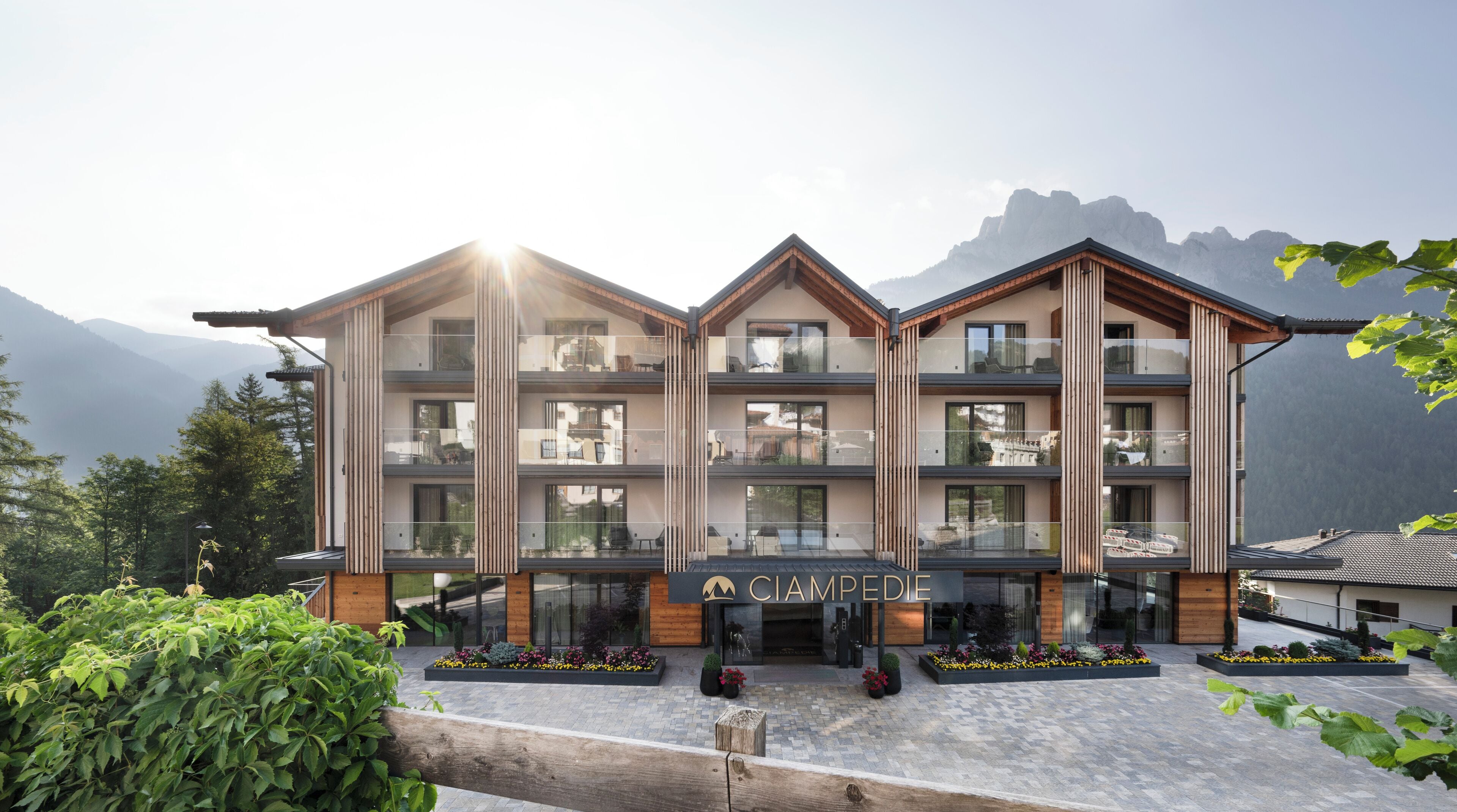 Un hotel de varios pisos con diseño moderno, que cuenta con balcones y grandes ventanales.