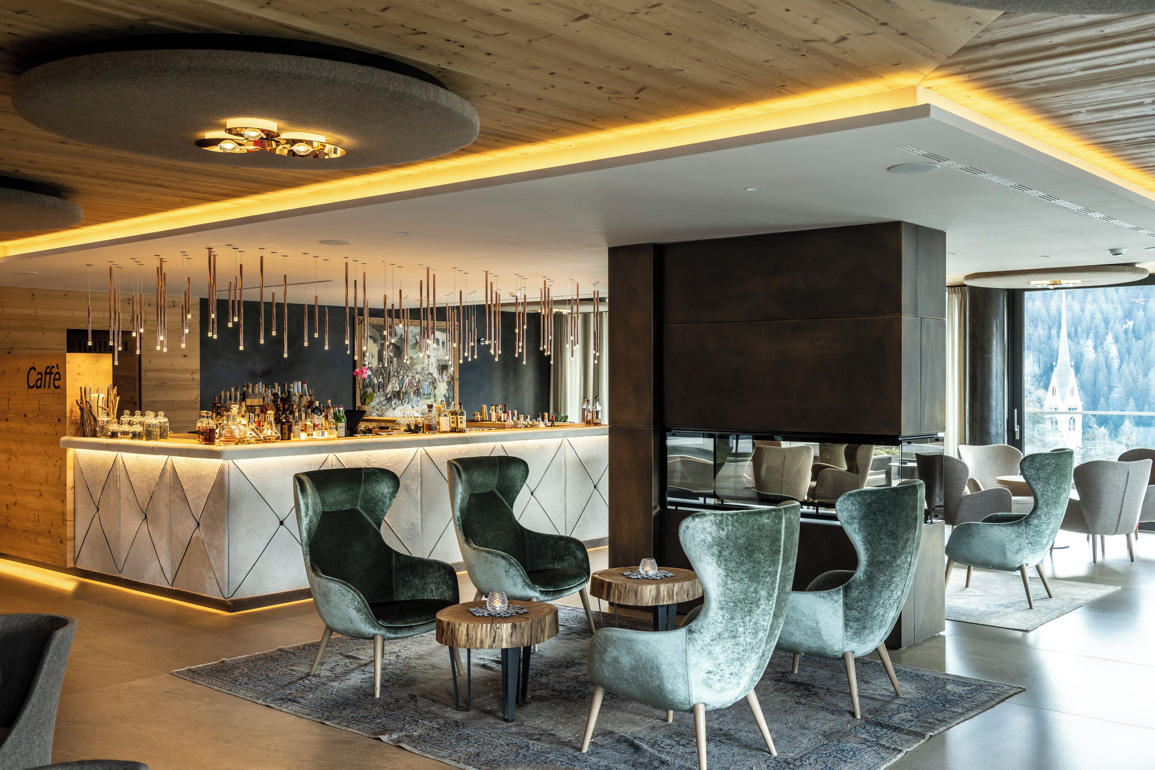 A modern bar area with a bar counter, hanging lights, and seating with round tables and chairs.