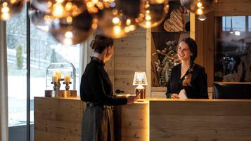 A reception desk with a wooden finish, a glass display case with candles, and a warm light fixture above.
