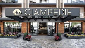 En hotellentrén med en tydlig skylt som visar namnet ”CIAMPEDIE” och en logotyp föreställande ett berg.