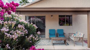 A modern house with a patio featuring two blue chairs, a wooden table, and a potted plant. - Quiet Escape- Family Getaway by Trails and Shopping (Tucson)