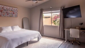 A bedroom with a bed, a desk, a chair, a ceiling fan, a TV, and a window with curtains. - Quiet Escape- Family Getaway by Trails and Shopping (Tucson)