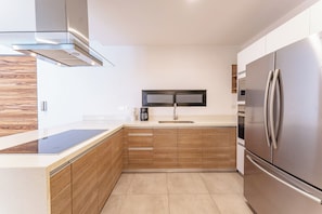 Eine moderne Küche mit Edelstahlkühlschrank, Holzschränken und eingebauter Mikrowelle.