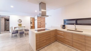 A modern kitchen with a central island, wooden cabinetry, a stainless steel range hood, and a dark backsplash. - Bright and Nice 3 Beds Close to 5th (Playa del Carmen)