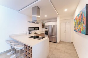 A modern kitchen with a central island, stainless steel appliances, and a minimalist design. - Bright and Nice 3 Beds Close to 5th (Playa del Carmen)