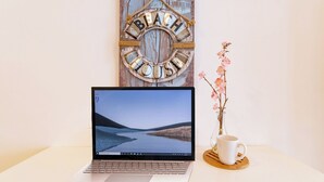 A laptop on a table with a wooden sign in the background and a vase with flowers. - Bright and Nice 3 Beds Close to 5th (Playa del Carmen)